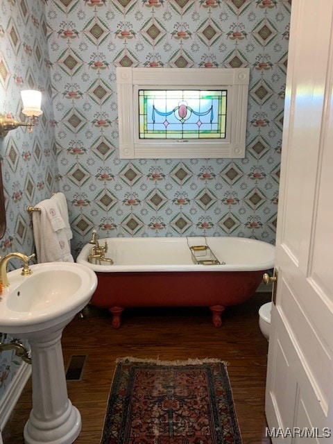 bathroom with a bathtub, hardwood / wood-style flooring, and toilet