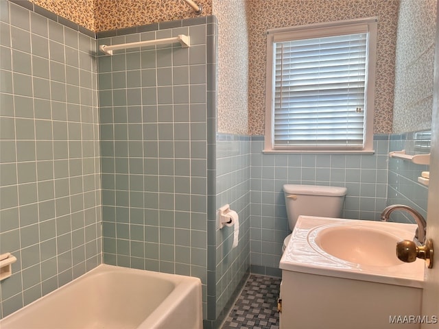 full bathroom with vanity, tiled shower / bath combo, toilet, and tile walls