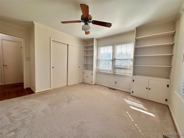 unfurnished bedroom with a closet, ceiling fan, crown molding, and light colored carpet