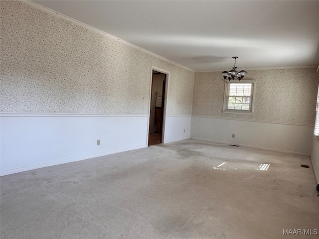 spare room with crown molding, carpet floors, and a chandelier