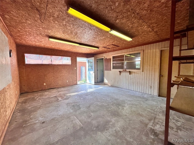 empty room with wood walls and concrete flooring