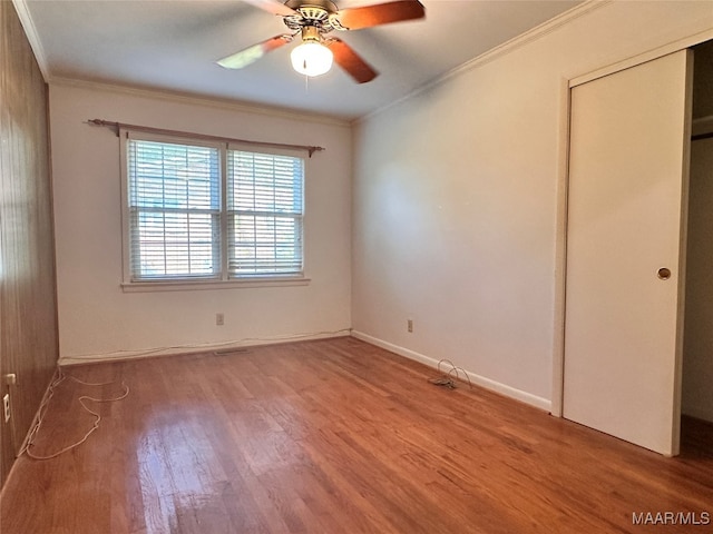 unfurnished bedroom with a closet, ceiling fan, hardwood / wood-style flooring, and ornamental molding