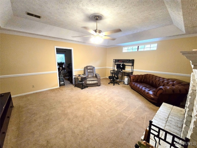 living room featuring ceiling fan, a raised ceiling, crown molding, a textured ceiling, and carpet