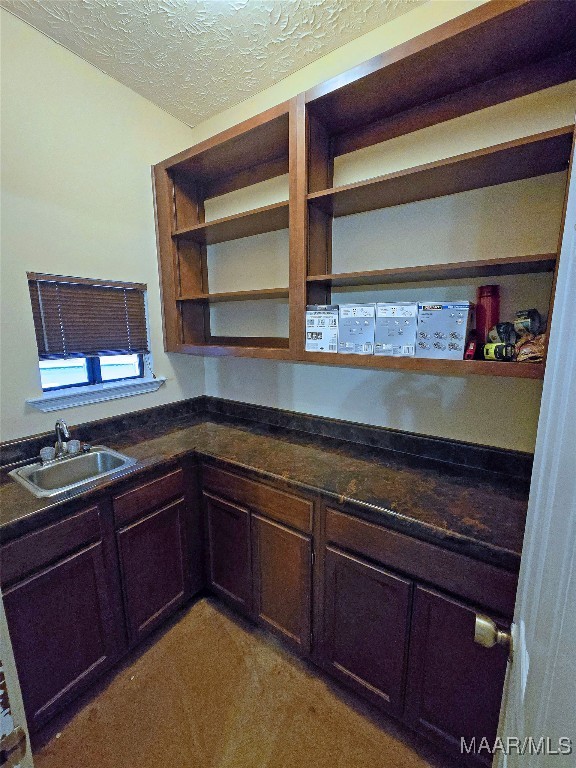 kitchen featuring a textured ceiling, light colored carpet, and sink