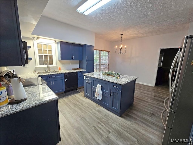 kitchen featuring black dishwasher, light wood finished floors, freestanding refrigerator, a sink, and blue cabinets