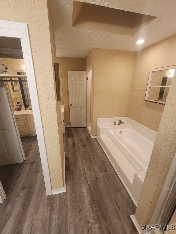 bathroom with a bathtub, vanity, wood-type flooring, and a textured ceiling