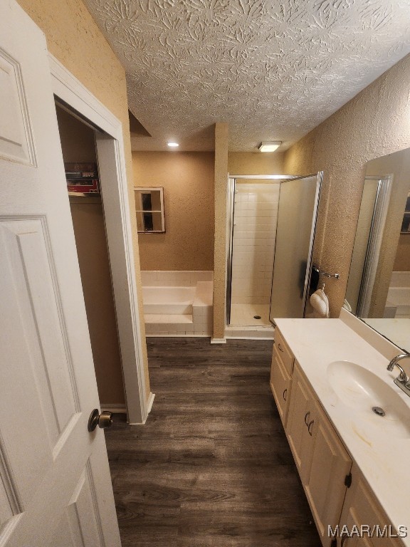 bathroom with vanity, a textured ceiling, hardwood / wood-style flooring, and a shower with door