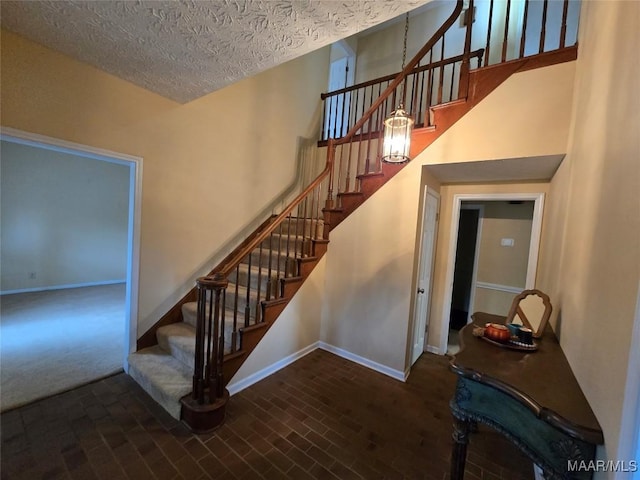 stairs with a towering ceiling, baseboards, and a textured ceiling