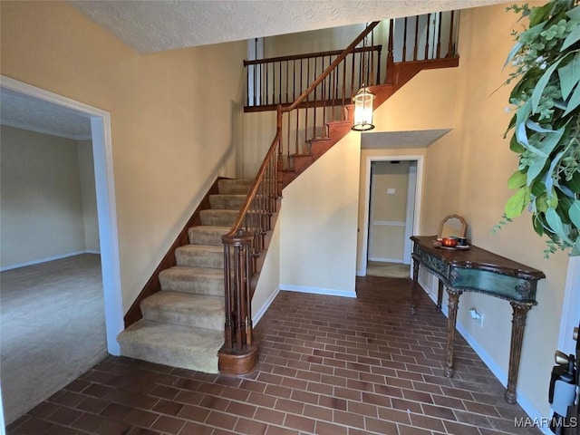 stairway featuring a textured ceiling and baseboards