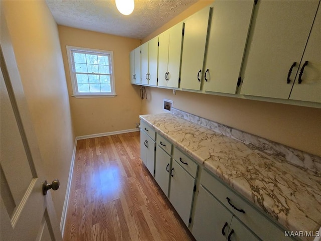 kitchen featuring a textured ceiling, light countertops, light wood finished floors, and baseboards