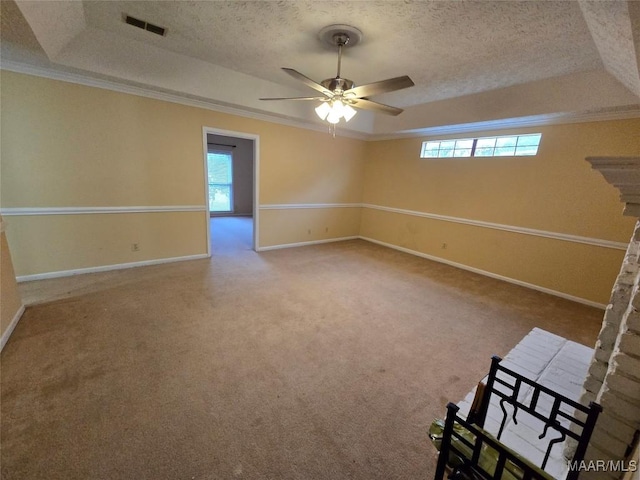 carpeted empty room featuring baseboards, a tray ceiling, a textured ceiling, and ornamental molding