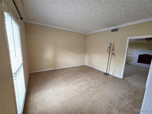 carpeted spare room featuring a textured ceiling, visible vents, baseboards, ornamental molding, and a brick fireplace