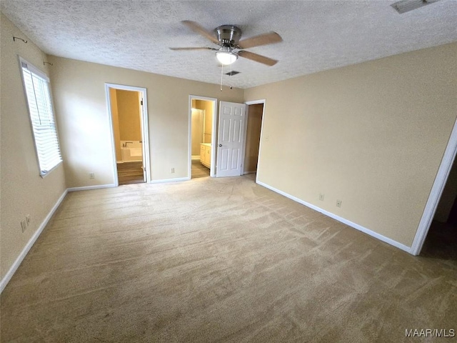 unfurnished bedroom with ensuite bathroom, carpet floors, a textured ceiling, and baseboards