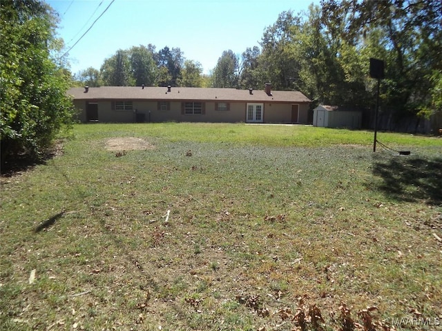 view of green lawn featuring a storage unit, an outdoor structure, and french doors