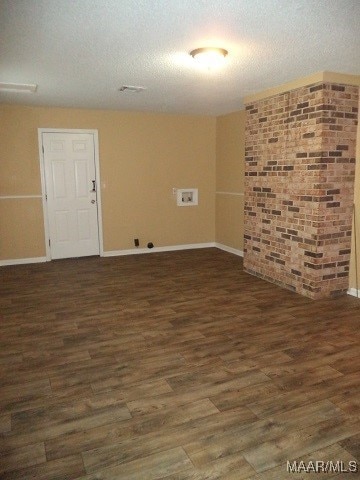 spare room featuring dark wood-type flooring and a textured ceiling