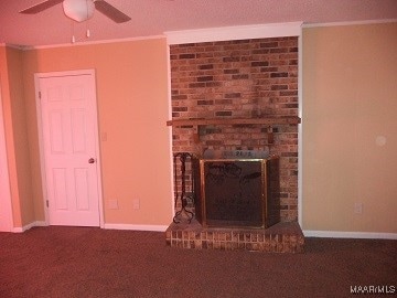 unfurnished living room featuring ornamental molding, ceiling fan, carpet flooring, and a brick fireplace