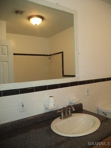 bathroom with tile walls, toilet, and vanity