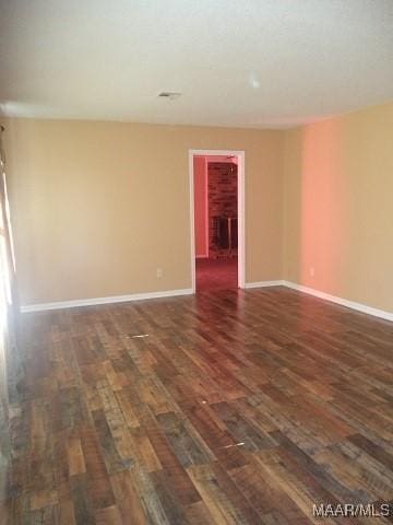 empty room featuring dark wood-style floors and baseboards