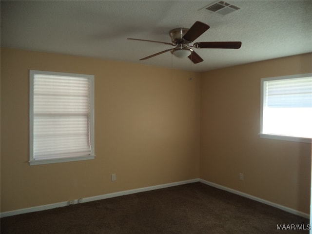 spare room with dark colored carpet, a textured ceiling, and ceiling fan