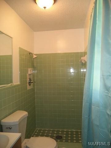 full bathroom with tile walls, toilet, tile patterned floors, a tile shower, and vanity