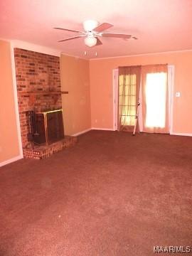unfurnished living room featuring a ceiling fan, baseboards, a fireplace, carpet flooring, and crown molding