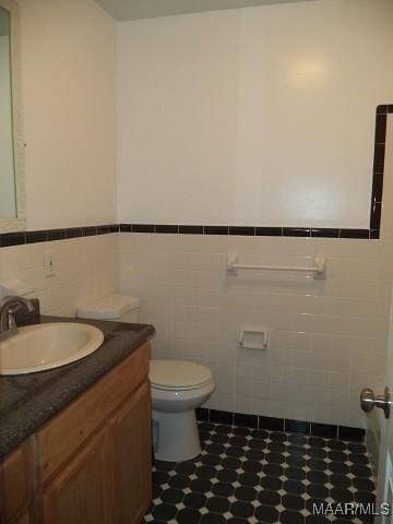 bathroom featuring wainscoting, tile walls, vanity, and toilet
