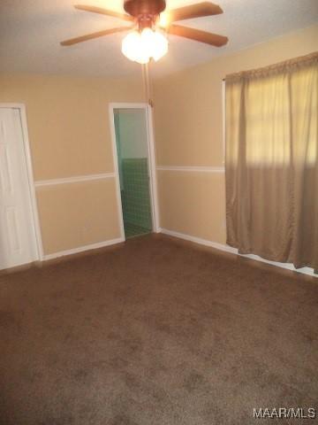 empty room with a ceiling fan, carpet floors, and baseboards