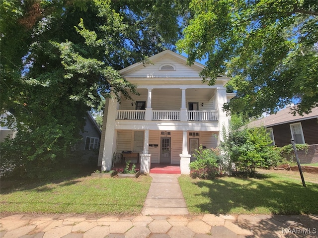 greek revival inspired property featuring a front lawn, covered porch, and a balcony