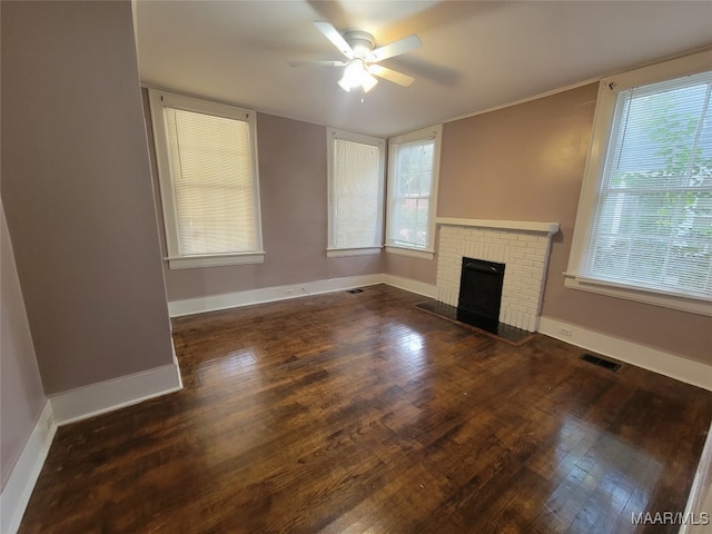 unfurnished living room featuring ceiling fan, a healthy amount of sunlight, a fireplace, and dark hardwood / wood-style floors