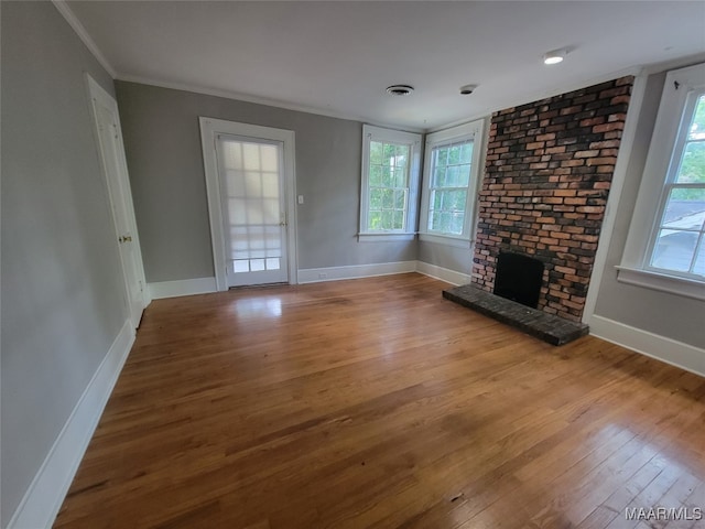 unfurnished living room with crown molding, a brick fireplace, and wood-type flooring