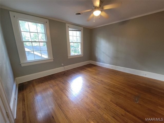 empty room featuring crown molding, dark hardwood / wood-style floors, a healthy amount of sunlight, and ceiling fan