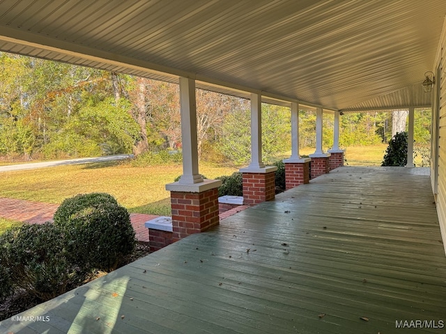 wooden terrace featuring a lawn and covered porch