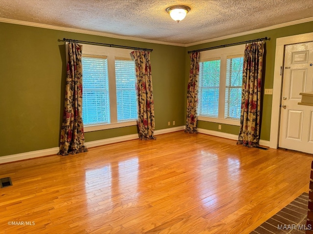 spare room featuring a textured ceiling, light wood-type flooring, and ornamental molding