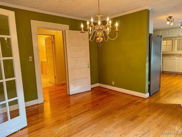 unfurnished dining area with a textured ceiling, an inviting chandelier, light hardwood / wood-style flooring, and crown molding