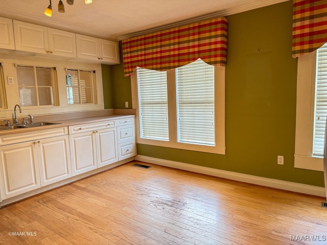 kitchen featuring white cabinets, light hardwood / wood-style floors, and sink