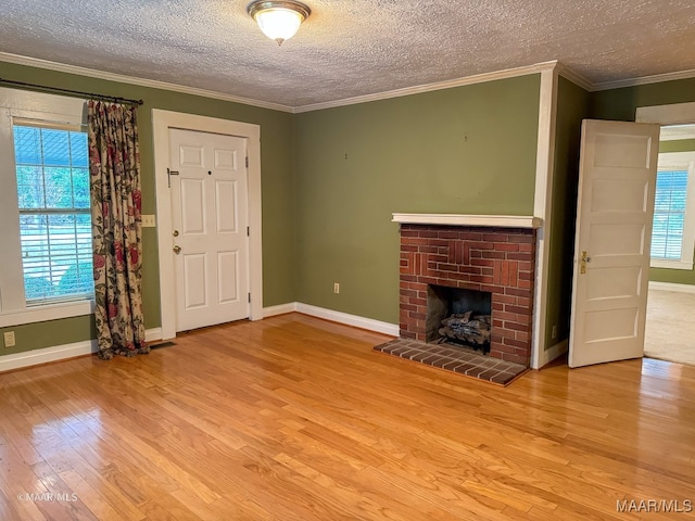 unfurnished living room with a fireplace, a textured ceiling, light wood-type flooring, and crown molding