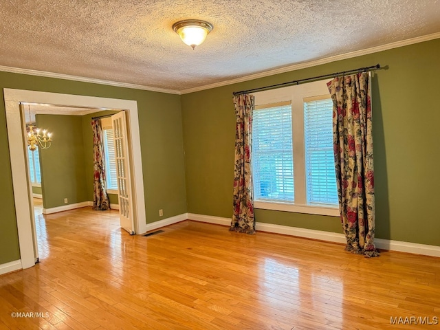 unfurnished room with crown molding, wood-type flooring, a textured ceiling, and a notable chandelier