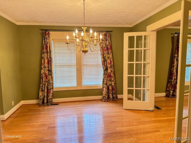 unfurnished dining area featuring wood-type flooring, a healthy amount of sunlight, and a notable chandelier