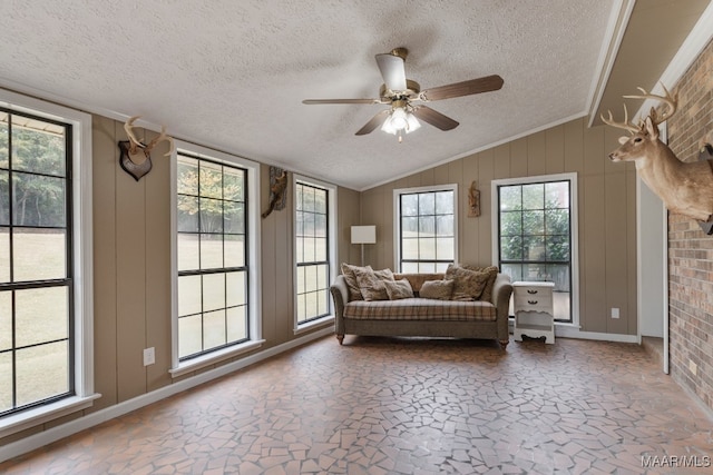 interior space featuring lofted ceiling, a textured ceiling, wood walls, and ceiling fan