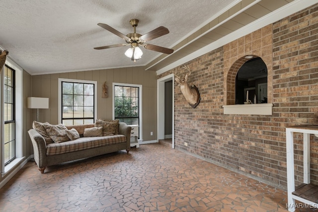 living room with brick wall, vaulted ceiling, a textured ceiling, and ceiling fan