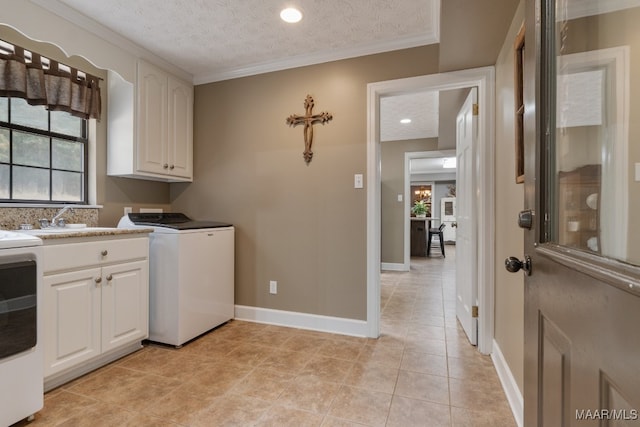 laundry area with a textured ceiling, washer / clothes dryer, cabinets, and a wealth of natural light