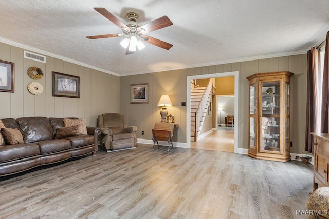 living room with crown molding, light hardwood / wood-style flooring, a textured ceiling, and ceiling fan