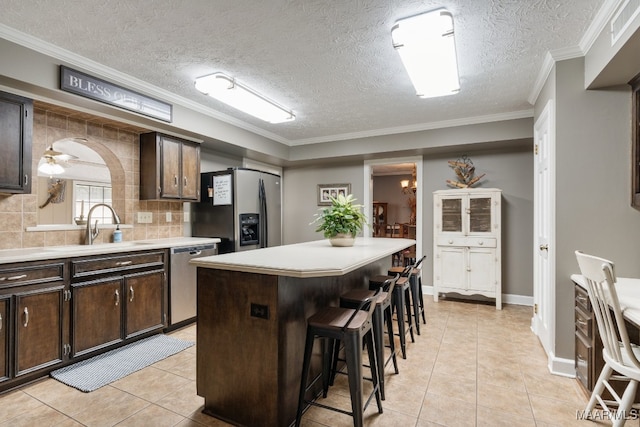 kitchen featuring dark brown cabinets, a center island, stainless steel appliances, decorative backsplash, and a breakfast bar