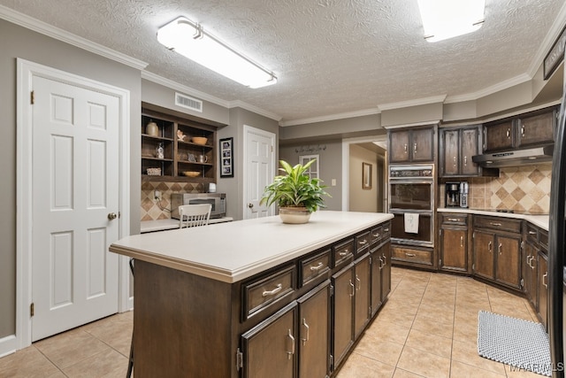 kitchen with light tile patterned flooring, a textured ceiling, dark brown cabinetry, and a center island