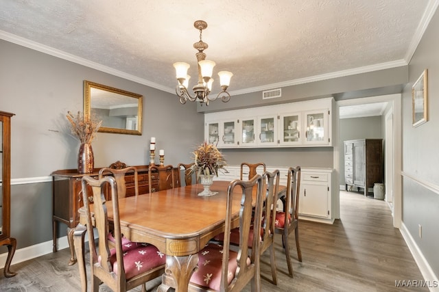 dining space with an inviting chandelier, ornamental molding, a textured ceiling, and dark hardwood / wood-style flooring