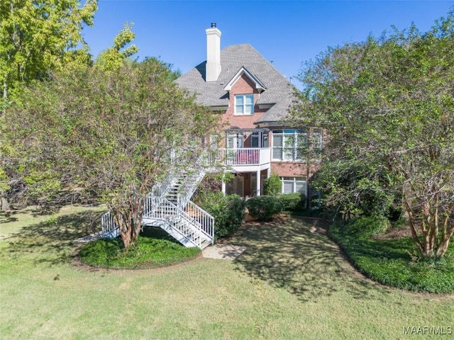 back of house with stairway, a chimney, a wooden deck, and a lawn