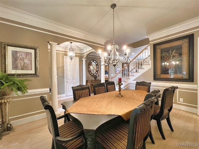 dining room featuring arched walkways, crown molding, decorative columns, stairway, and light wood-style flooring