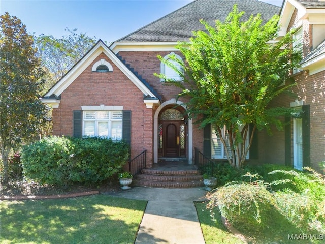 view of front of home with roof with shingles and brick siding