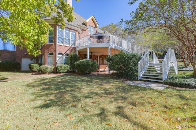 view of front of home featuring ceiling fan, brick siding, stairway, and a front lawn