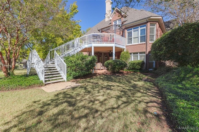 view of front of house with brick siding, stairway, a wooden deck, a front lawn, and a chimney